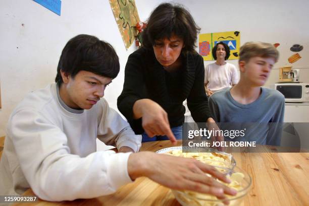 Une éducatrice aide des adolescents autistes à réaliser une tarte aux pommes, le 20 mai 2003, lors d'un atelier cuisine à l'institut médico-éducatif...