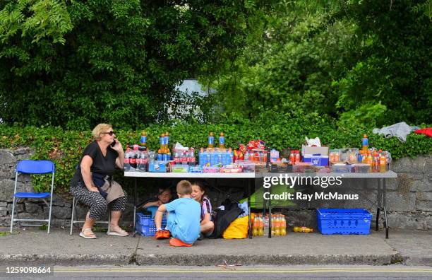 Limerick , Ireland - 24 June 2023; A street trader makes a phone call as three children take shelter under her stall before the GAA Hurling...