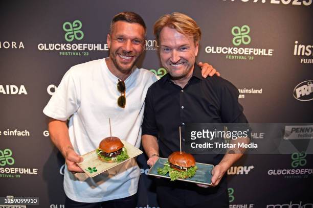 Lukas Podolski and Markus Krampe with their Glücksburger" during the "Glücksgefühle Festival Warm Up" at Hans im Glück am Ring on June 26, 2023 in...
