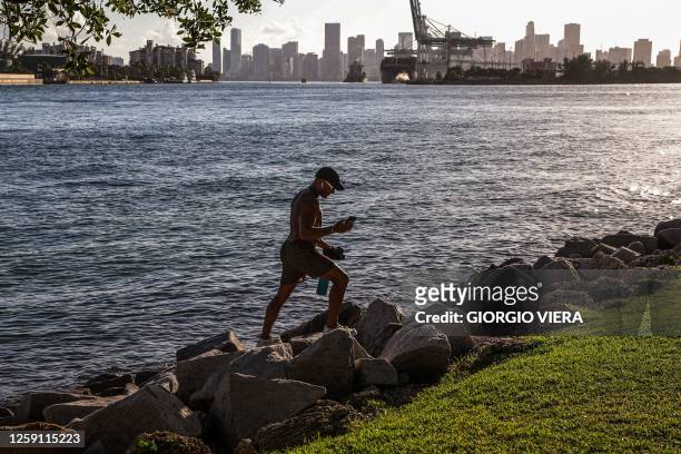 Man walks among the rocks of South Point Park in Miami Beach, Florida, during a heat wave on June 26, 2023.