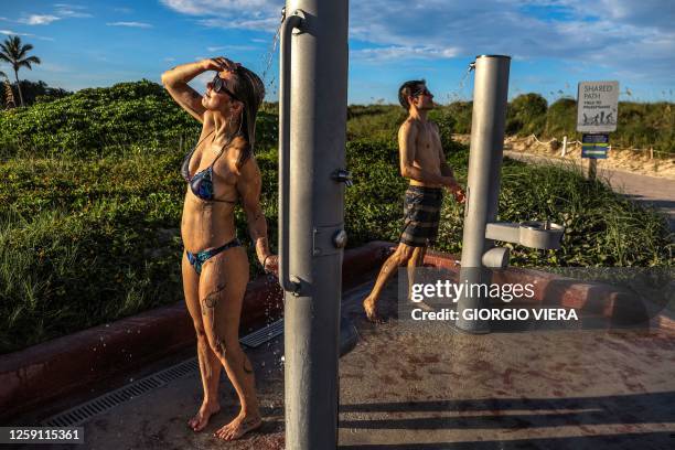 People use showers to cool off from the heat after getting out of the ocean in Miami Beach, Florida during a heat wave on June 26, 2023.