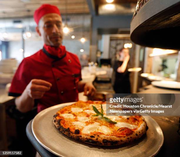 Enoteca Rossa sous chef and pizzaiolo Carlo Alberto looks over a Margherita pizza fresh out of the wood-fired oven Friday, May 13 in Houston.