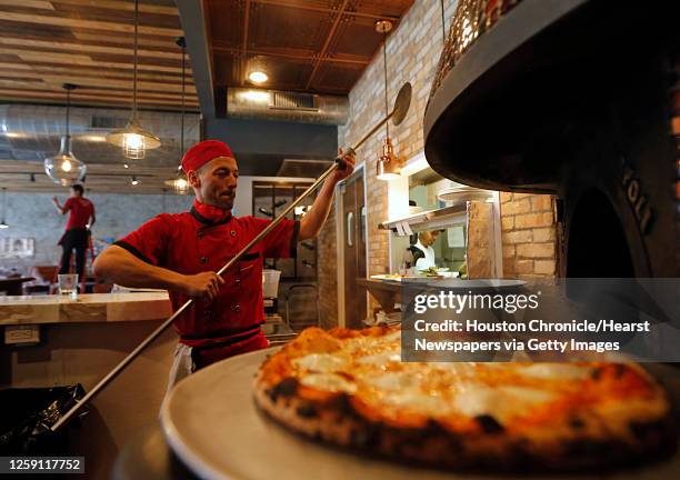 Enoteca Rossa sous chef and pizzaiolo Carlo Alberto removes a Margherita pizza from the wood-fired oven Friday, May 13 in Houston.