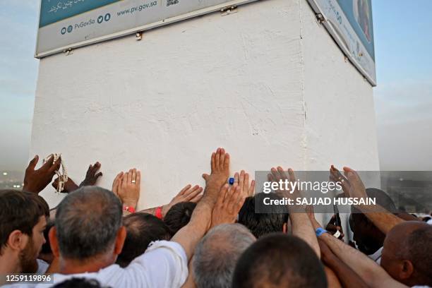 Muslim pilgrims touch the pillar atop Saudi Arabia's Mount Arafat, also known as Jabal al-Rahma or Mount of Mercy, during the climax of the Hajj...