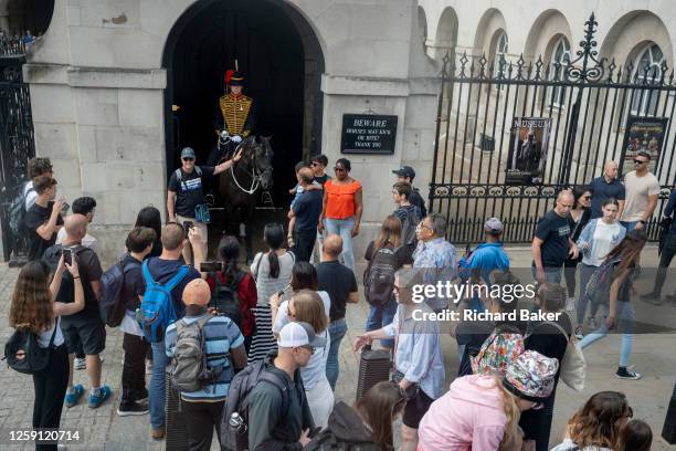 Visitors to the capital admire a mounted member of the armed services at Horseguards on Whitehall, on 26th June, in London, England.