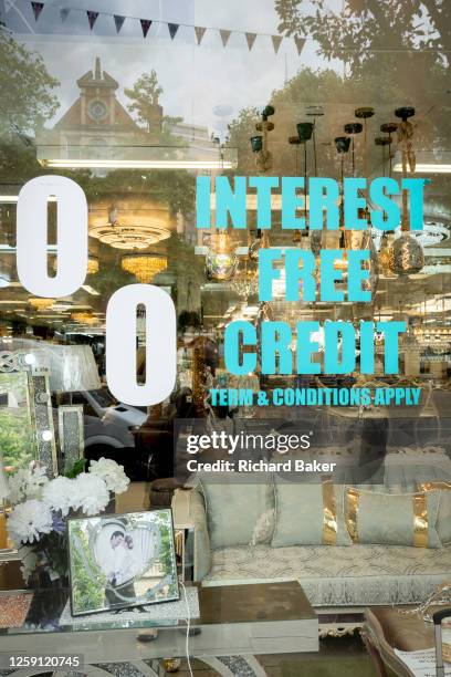 With a portrait of a happy couple in a picture frame, a furniture and home fixtures business advertises interest free credit in ts window in Ealing,...