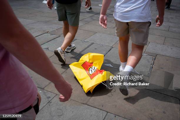 Passers-by walk near an empty Lego branded shopping bag near to their Leicester Square store on 26th June, in London, England.