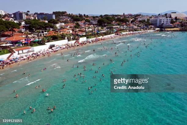 Citizens and tourists spend time Guvercinada and Kadikkalesi beaches ahead of eid holiday to cool off on June 26 at Kusadasi district in Aydin,...