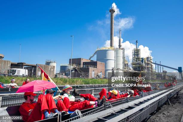 Protesters sit on a conveyer belt that transports Iron ore pellets for steel production, during the demonstration. Climate activists, Greenpeace and...