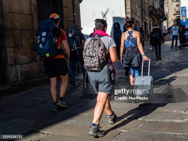 Pilgrim carrying a suitcase is seen entering Santiago, the end of the Camino de Santiago, with other pilgrims. On June 2nd, 2023.