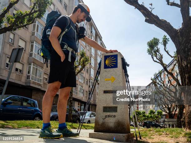 Pilgrim is looking at the pylon that marks 100 km to Santiago, on the route of the Camino Primitivo in Galicia, Spain. On May 29th, 2023.