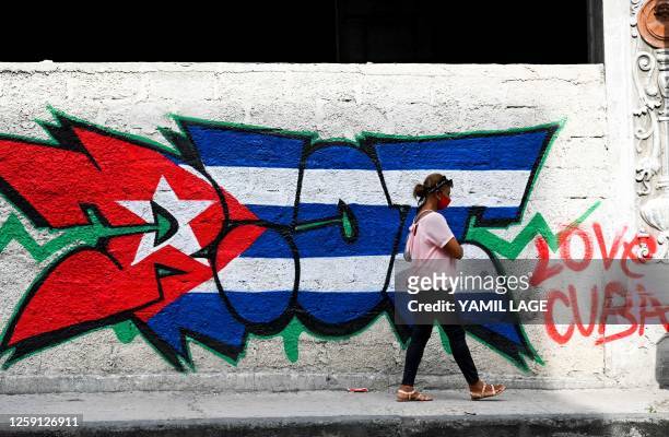 Woman walks past graffiti of the Cuban flag in a street in Havana on June 27, 2023.