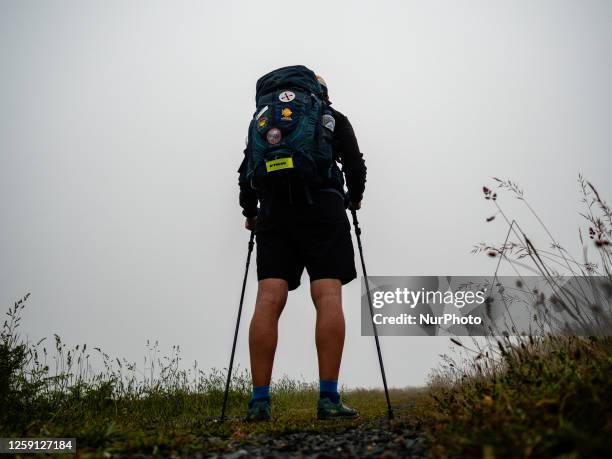 Man is seen walking in a dense morning fog, while walking the Camino Primitivo route, in Galicia, Spain. On May 31st, 2023.