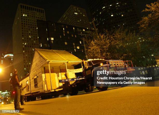 David Bear with Cherry House Moving keeps his eye onoverhead lines as a 19th century Fourth Ward cottage is being moved in downtown Houston by the...