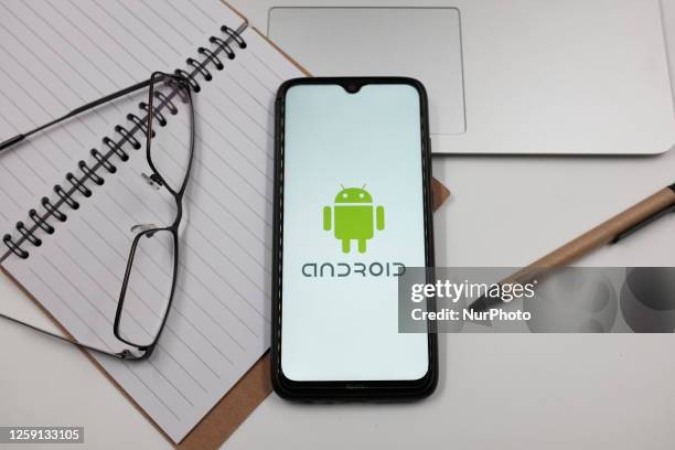 In this photo illustration an Android logo is displayed on a smartphone screen above a notebook next to glasses and a pen in Athens, Greece on June...
