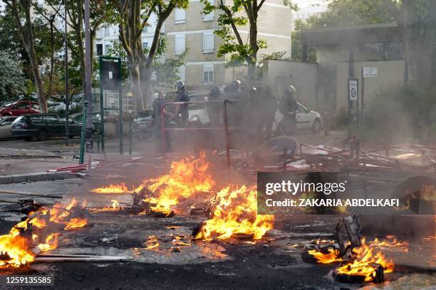 Police in riot gear stand next to a fire burning in the street after a demonstration in Nanterre, west of Paris, on June 27 after French police...