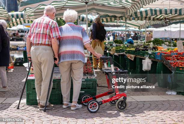 June 2023, Saxony, Leipzig: Two senior citizens stand with walkers and rollators at the weekly market in downtown Leipzig. The approximately 21...