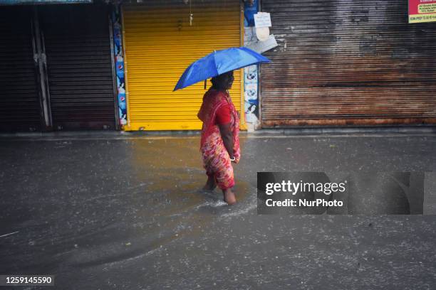 Woman holds an umbrella while walking along a flooded street during heavy rain in Kolkata, India on June 28, 2013.
