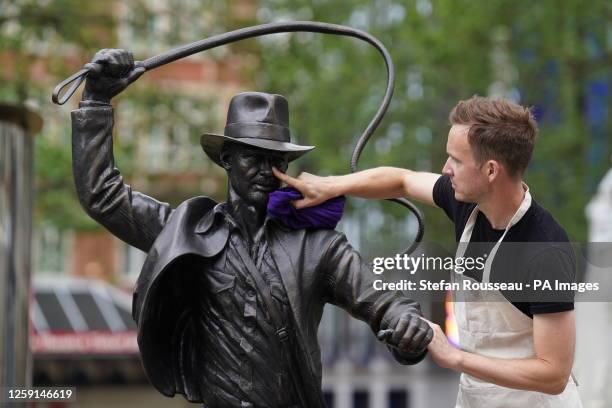 Life-sized bronze statue of the character Indiana Jones being cleaned as it's unveiled as the latest addition to the Leicester Square's 'Scenes in...