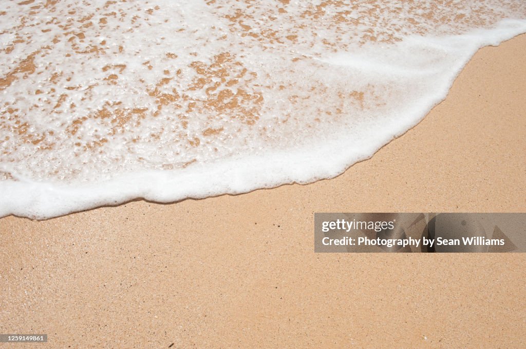 Close up shoreline of receding waves in Maui
