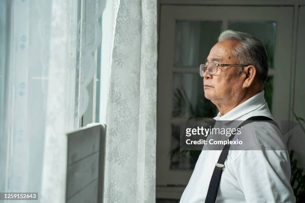 孤独を感じて窓の外を見て眼鏡をかけたペンシブな老人をクローズアップ。70年代のアジアの年金受給者は、子供と妻を行方不明。 - old man and glasses ストックフォトと画像