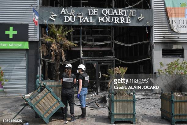 French technical and scientific police officers examine the facade of a burnt-down annex town hall of the Le Val Fouree neighbourhood in...
