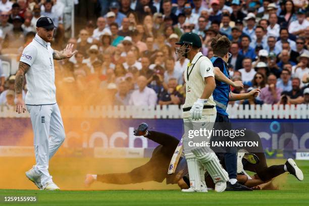 Just Stop Oil protester is stopped by a member of security after entering the pitch to throw orange powder during the day one of the second Ashes...