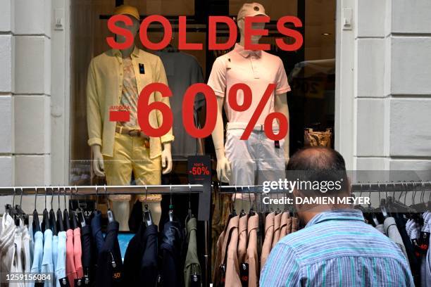 Man looks at a rack of clothes on the first day of sales, "Les soldes", which last for four weeks, in Rennes, western France, on June 28, 2023.