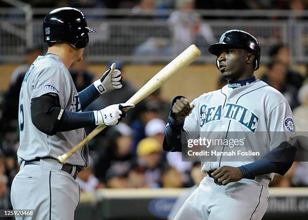 Kyle Seager of the Seattle Mariners congratulates Trayvon Robinson on scoring against the Minnesota Twins in the seventh inning on September 21, 2011...