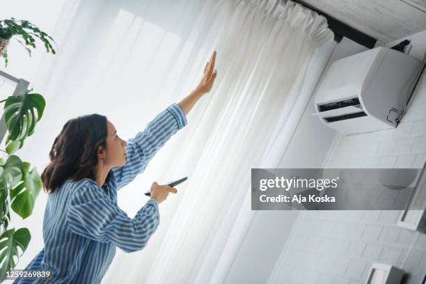 turning on the air conditioner. - cold house stock pictures, royalty-free photos & images