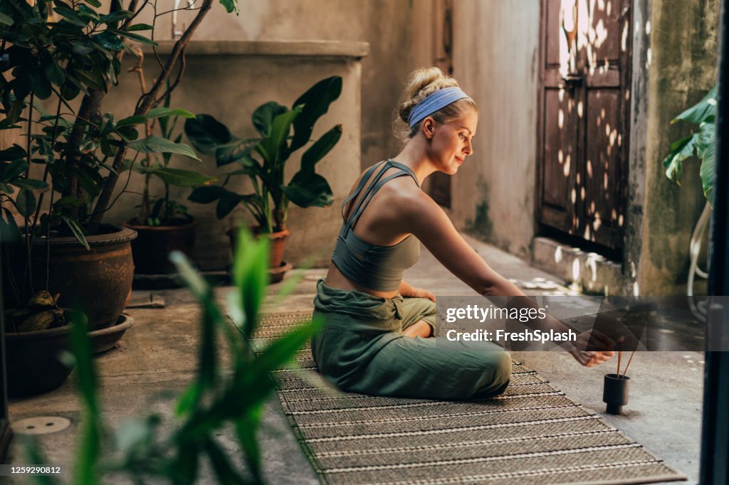 Yoga im Garten: eine Frau, die Yoga macht, während sie den Duft von natürlichen Räucherstäbchen genießt