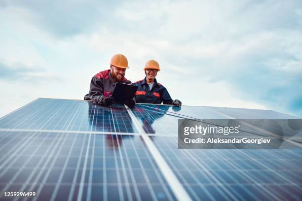 senior werknemer helpen jongere mannelijke maatregel zonnepaneel afmetingen - energie industrie stockfoto's en -beelden