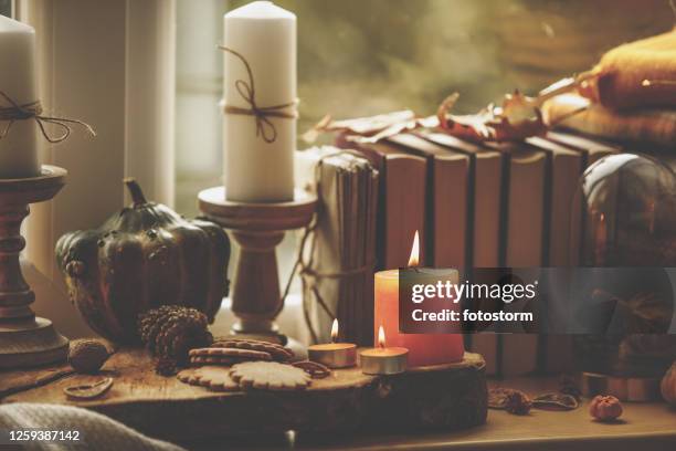 close-up composition of candles, green pumpkin, cookies and set of books - book embellishment stock pictures, royalty-free photos & images