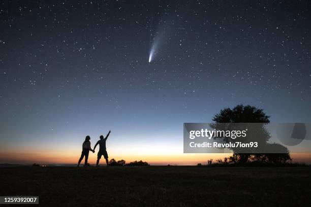 junges paar beobachtet den neowise komet unter dem hellen nachthimmel - sternenspur stock-fotos und bilder
