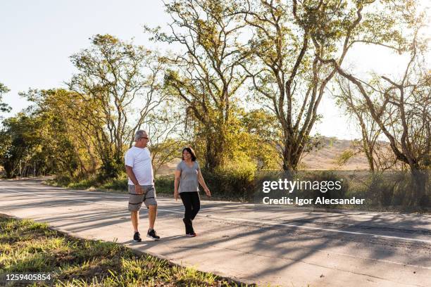 senior-paar zu fuß am straßenrand - vorruhestand stock-fotos und bilder