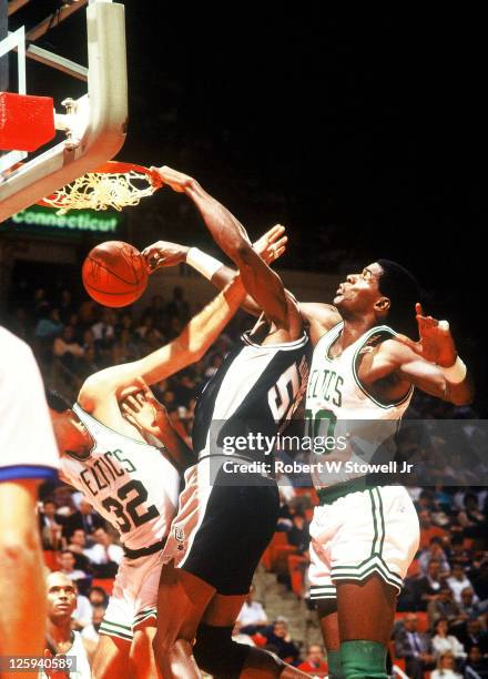 Center David Robinson of the San Antonio Spurs dunks the ball despite the intense defense applied by the Boston Celtics' Robert Parish, Hartford, CT,...