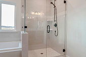 Bathroom shower stall with half glass enclosure adjacent to built in bathtub
