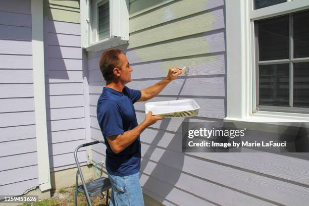 man painting exterior of house with paint brush - ペンキトレー ストックフォトと画像