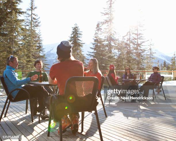 friends drink beer on ski lodge patio - whistler bc stock pictures, royalty-free photos & images