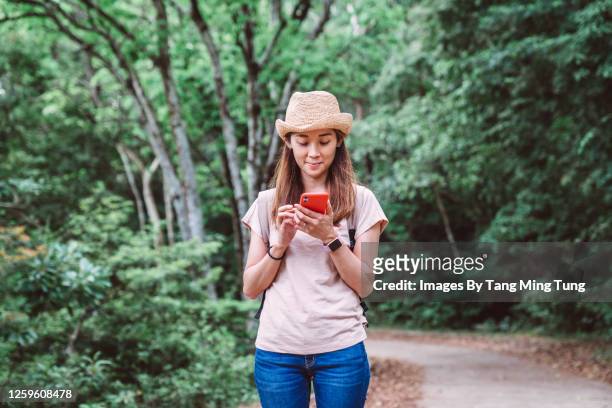 pretty young woman using gps navigation with her smartphone while hiking on woodland trail - china tourism stock pictures, royalty-free photos & images