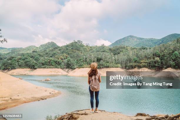 rear view of young pretty woman enjoying a scenic beautiful lake view joyfully while she is hiking on nature trail - hong kong mountain stock pictures, royalty-free photos & images