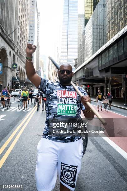 July 26: Hawk Newsome, Chairperson of Black Lives Matter Greater New York walks past Grand Central Station holding a flag that says "Black Lives...