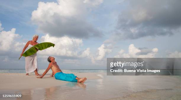 senior couple on a tropical beach - vista posterior stockfoto's en -beelden