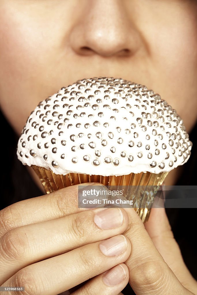 Close-up shot of a lady holding a jewelled cupcake