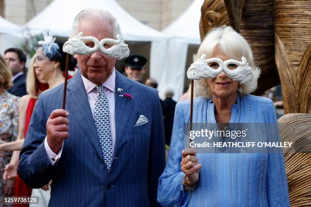 Britain's King Charles III and Britain's Queen Camilla hold masks as they attend the Animal Ball at Lancaster House in London on June 28 to mark the...