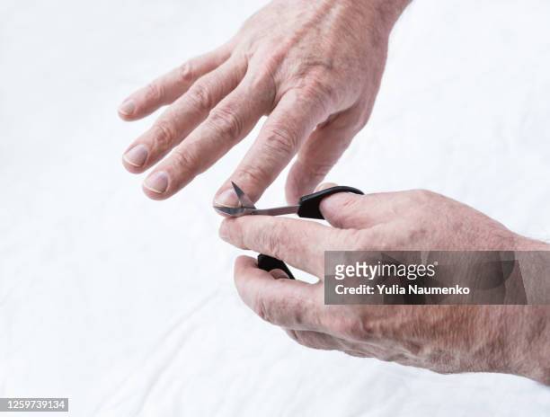 man cutting his nails. making manicure at home. men spa hygiene. hands of an elderly man close-up, a man does a manicure at home, cuts and files nails with a file. - nagelhaut stock-fotos und bilder