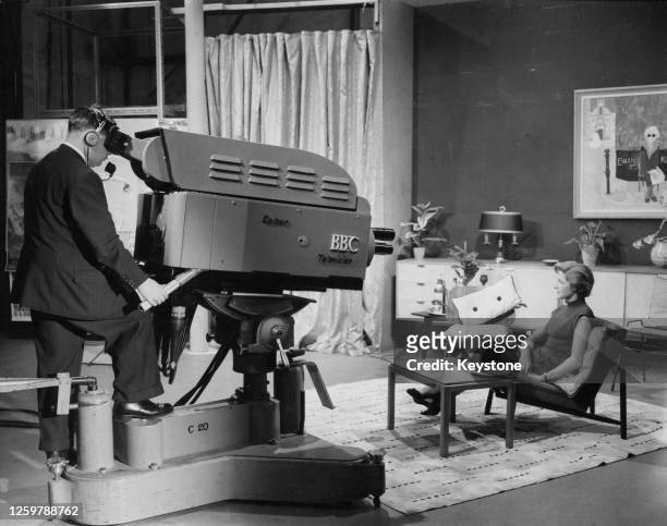 Secretary to the Head of the Television Section, Designs Department, Ann Veronica Matthews sits on a chair as she is filmed by a colour television...