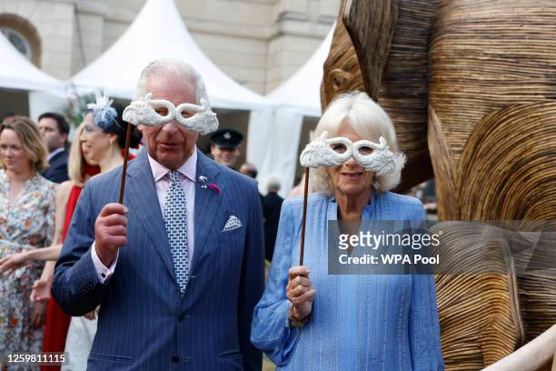 King Charles III and Queen Camilla pose with masquerade masks as they attend the Animal Ball at Lancaster House to mark the 20th anniversary of...