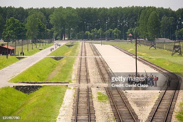 guided tour stands on unloading platform where prisoners would have been selected and separated in birkenau, auschwitz concentration camp in poland - nazi concentration camp stock pictures, royalty-free photos & images