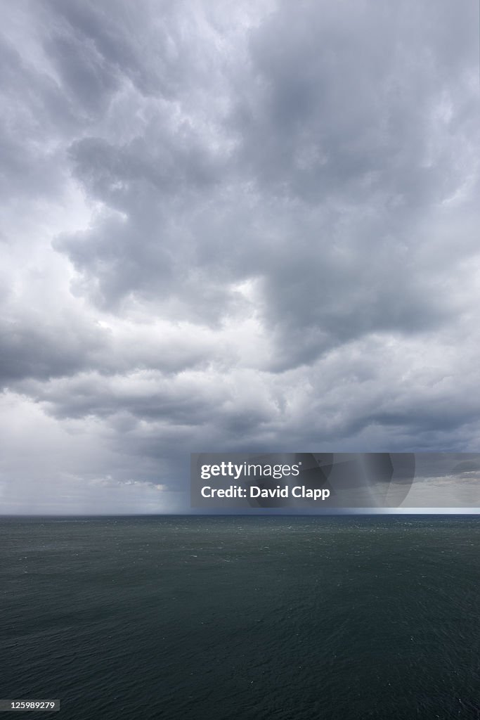 Massive cumulonimbus cloud releases deluge of rain off Flamborough cliffs in East Yorkshire, England, UK